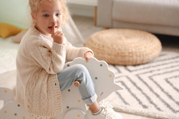 Cute little girl playing with rocking horse at home