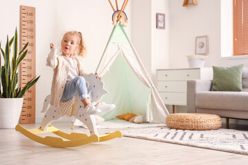Cute little girl playing with rocking horse at home - Powered by Adobe