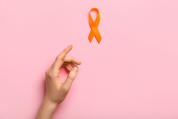 Woman with orange awareness ribbon on pink background. Kidney cancer concept