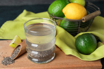 Glass of healthy drink with chia seeds, citrus fruits and scoop on wooden board
