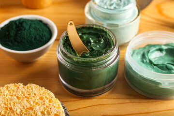 Jars of spirulina facial mask on wooden background, closeup