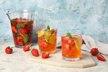 Glasses of strawberry lemonade on table against grunge background