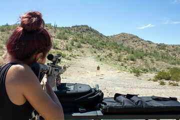 Young lady shooting a .22LR rifle gun downrange Arizona desert at targets