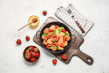Mini pancakes, strawberry and honey on light background