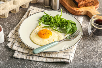 Plate with tasty fried egg and greens on table