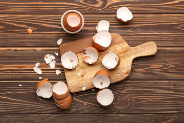 Board with broken egg shells on wooden background