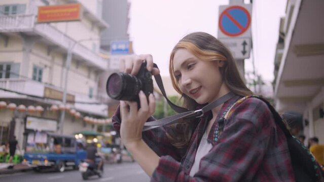A beautiful woman tourist enjoys taking photos of the city view in Bangkok, Thailand.