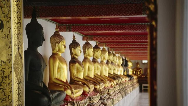 Gold Buddha Statues in Bangkok, Famous Thailand Buildings with a Line of Lots of Buddhist Statues in a Row at Beautiful Wat Pho (Temple of the Reclining Buddha), a Famous Tourist Destination