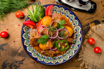 Kazan kebab on plate with fried potatoes and sauce top view