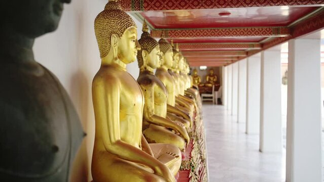 Gold Buddha Statues in Bangkok, Famous Thailand Buildings with a Line of Lots of Buddhist Statues in a Row at Beautiful Wat Pho (Temple of the Reclining Buddha), a Famous Tourist Destination