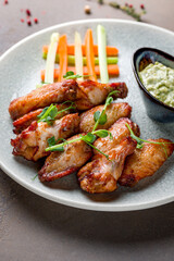 Buffalo chicken wings with sauce on plate on brown table macro close up, vertical