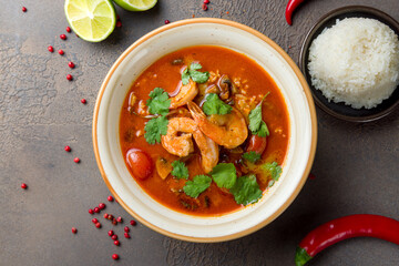 Tom Yam soup with rice and shrimps on brown table top view
