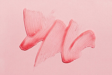 Smears of transparent shining lip gloss on a pink background