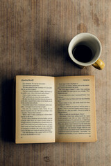 An open book with blurred pages and a cup of coffee. Melancholy