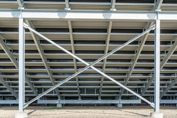 Straight on view of under stadium bleachers, steal I-Beam bleachers with X cross brace, with stone surface.
