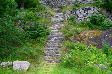 Obraz premium Stone stairs leading up a stone and grass hill, path to adventure 