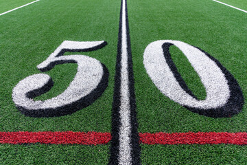 Synthetic turf football 50 yard line in white with black number shadow along with red lacrosse line...