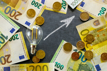 Electricity cost.Rising electricity prices in Europe. Light bulb,euro bills and euro coins, up...