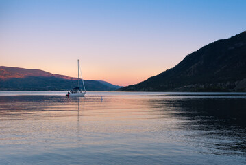 View of Okanagan Lake and sailboat at sunset in summer