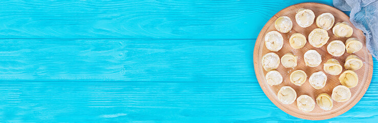 Homemade raw dumplings, pelmeni, on wooden background. Banner.