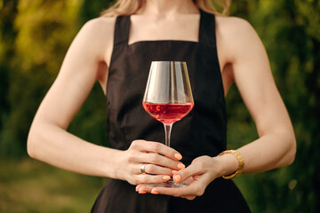 a glass of rose wine in the hands of a woman in close-up, nature, winery	