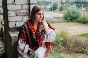 Art work on the theme of the war in Ukraine. A crying Ukrainian woman in national dress sits in the window frame of a building bombed by the Russian army.