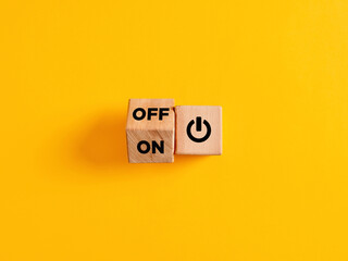 The words on and off on wooden cubes with start icon on yellow background. Power on off switch or...