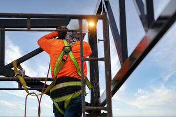 Industrial steel roof truss welders wear safety clothing on the construction site. Fall arrestor...