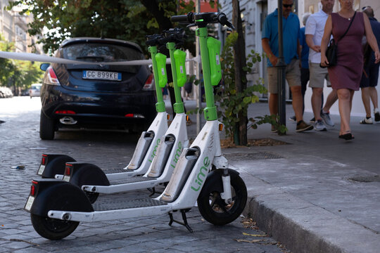 ROME, ITALY - JULY 16 2022: E-scooters or e-steps of the company LIME for rent are waiting for customers in a shopping street in Rome. It is a popular means of transport there. E-mobility