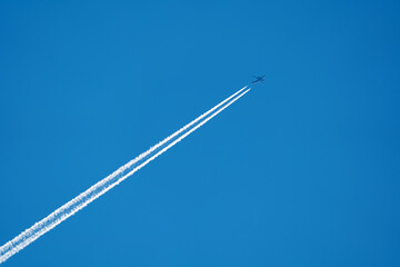 a flying plane with a white smoke trail on a blue sky background