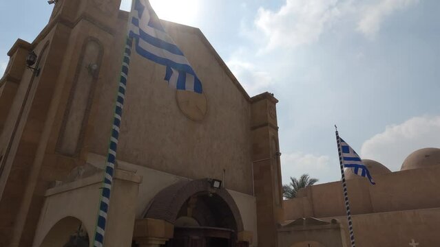 Greek Flags Blowing In Wind Outside Sleeping Mary Church In Coptic Cairo. Pan Down