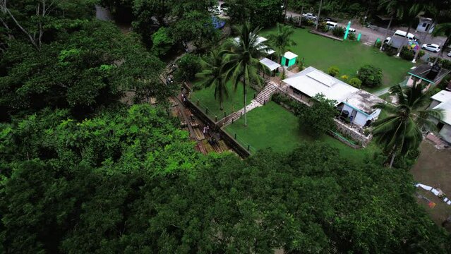 Aerial shoot of wharf next to rain forest and brown river with bamboo rafts in Jamaica
