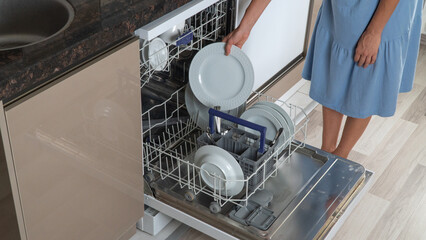 A woman pulls out a clean dish from a dishwasher