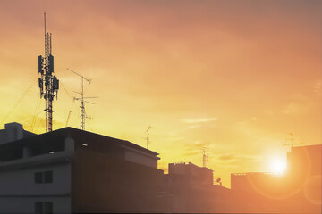 Silhouette image of communication antenna telephone network in the city with sunset sky background.