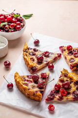 Slices of clafoutis with cherry on baking paper. Traditional homemade french cherry pie. Selective focus.
