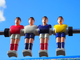 group of colored plastic foosball players on blue sky background