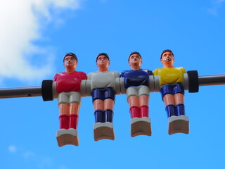 Obraz premium group of colored plastic foosball players on blue sky background