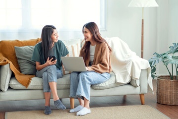 Two woman communicate with their friends and classmates via video link using a laptop and smartphone in the living room. Friends, friendship, time together - Powered by Adobe