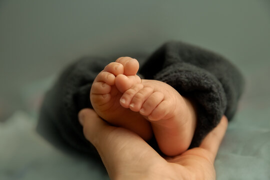 Feet of newborn baby in hand of mother, tiny toes of infant baby in a selective focus