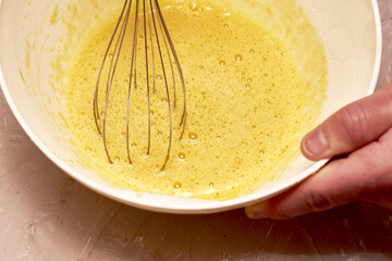 a man whips cream in a white cup with a whisk