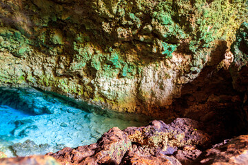 View of beautiful natural pool of crystal clear water formed in a rocky cave with stalagmites and stalagmites. Kuza cave in Zanzibar, Tanzania