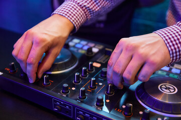 Dj playing music with turntables and sound mixer on stage in night club