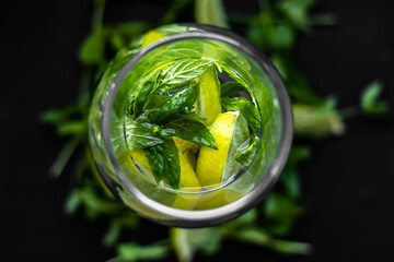 Lime slices and mint sprigs on a black background. Lime and mint. Summer freshness. Natural background. Ingredients of lemonade. Yellow and green colors in still life. A sprig of mint. Sliced lime.