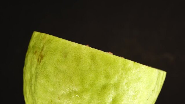 4K macro close up organic sliced guava rotating plate isolated on black background