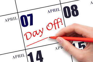7th day of April. Hand writing text DAY OFF and drawing a line on calendar date 7 April. Vacation...