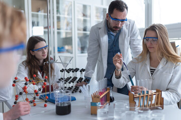 Science students with teacher doing chemical reaction experiment in the laboratory at university.