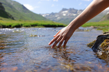 Woman wand touching river water in the mountain
