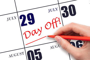 29th day of July. Hand writing text DAY OFF and drawing a line on calendar date 29 July. Vacation...