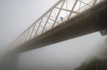 Woman walking alone across the bridge on a misty winter day