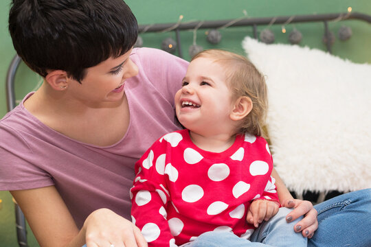 Smiling Mother And Daughter Playing On The Bed And Having Fun